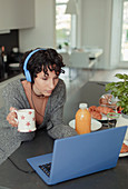 Woman with headphones working from home at laptop