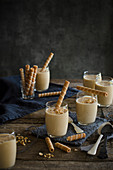 Nougat mousse dessert in glasses decorated with striped wafer rolls and nuts
