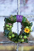 Moss wreath with green apples, ivy leaves, and flowers