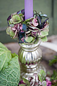 Candle with a wreath of hydrangea blossoms in a silver candlestick