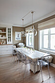 Langer Esstisch und transparente Stühle in der Küche mit beigefarbenen Wänden