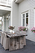 Rustikaler Holztisch mit eleganten Rattanstühlen auf der Terrasse
