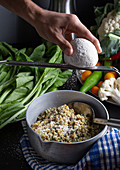 Levante Küche: Freekeh mit Spinat und Knoblauch, darüber Jameed (hartes, trockenes Laban) reiben