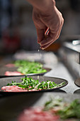 Koch würzt Salat in französischem Restaurant