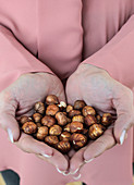 A woman holing a handful of hazelnuts