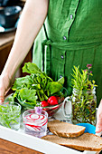 Woman serving flayoured water, bread, herbs and radish