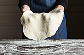 Baker holding rolled pastry dough over table