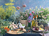 Still life with various herbs, herb vinegar, herb oil, garlic, spices