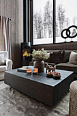 Coffee table in living room in natural colours with view of snowy landscape