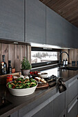 Dark fitted kitchen; food preparation on worktop