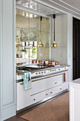 Elegant kitchen counter with hobs and cookers below mirrored wall