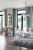 Opulent console table and mirror between French windows; dining area in foreground