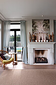 Armchair and side table in front of French windows next to fireplace