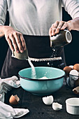 Woman adding sugar and flour in bowl