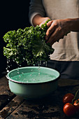 Washing green curly kale in bowl with water