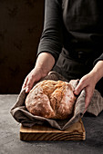 Hände halten frisch gebackenen Brotlaib