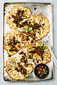 Cauliflower steaks with olive salsa on a baking tray