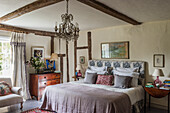 Doppelbett und antike Kommode im Schlafzimmer mit Holzbalken