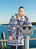 A young woman by the sea wearing a checked coat