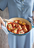 Woman holding roaster with Greek cabbage rolls