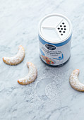 Erythritol icing sugar in a sprinkling tin next to vanilla crescents