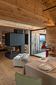 Fireplace in open-plan interior with wooden floor and wooden ceiling