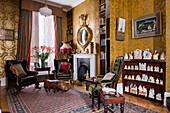 Gilded regency convex eagle mirror hangs above reinstalled regency chimney piece in drawing room with 1960s leather rhino, French ebonised chair upholstered in green velvet and Staffordshire figure collection