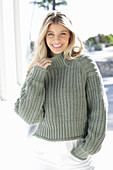 A young blonde woman wearing a grey knitted jumper