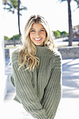 A young blonde woman wearing a grey knitted jumper