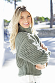 A young blonde woman wearing a grey knitted jumper