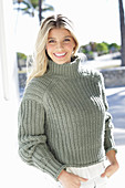 A young blonde woman wearing a grey knitted jumper
