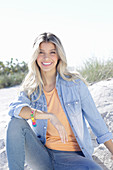 A young blonde woman wearing denim and an apricot top