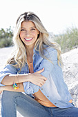 A young blonde woman wearing denim and an apricot top