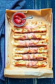 Baked sausages with cheese, wrapped with bacon