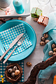 Blaues Tischgedeck österlich dekoriert mit Nest und Wachteleiern