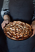 Woman holds a freshly baked apple tart in her hands