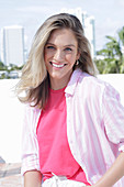 A young blonde woman wearing a pink top and a striped shirt