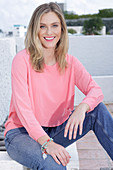 Junge blonde Frau in rosa Bluse und Jeans