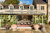 View into dining room of glass conservatory extension to 19th century stone farmhouse.