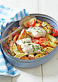 Gebratener Fisch auf griechische Art mit Kartoffeln, Tomaten und Zitronen