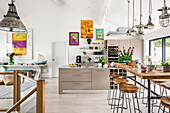 Reclaimed lights above breakfast bar with 1960s style artwork in open plan kitchen renovation