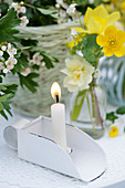 Lit candle next to posy of primroses, buttercups and tulips