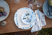 Blue and white place setting with menu card and silver cutlery on wooden table