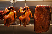 Gegrilltes Schweinefleisch und gegrillte Hühner aufgehängt an Haken (China)