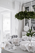Festively set dining table below suspended Christmas wreath