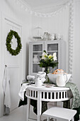 Round table, glass-fronted cabinet and door with Christmas wreath in kitchen