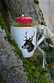 Red candle in a cup with deer decoration
