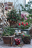Christmas terrace with Christmas tree, Advent wreath, baskets with fir branches, cones and Christmas tree decorations, mug with hot punch on wooden disc, antlers and old wooden skates as decoration