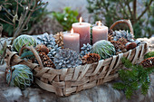 Korbtablett mit Kerzen, Christbaumkugeln und Zapfen