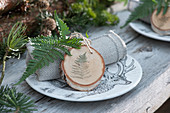 Homemade pendant made from a wooden disc with a fern leaf as a napkin decoration
